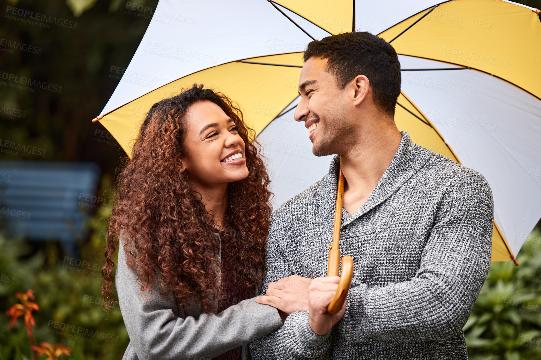 Buy stock photo Shot of a young couple standing in the rain with an umbrella