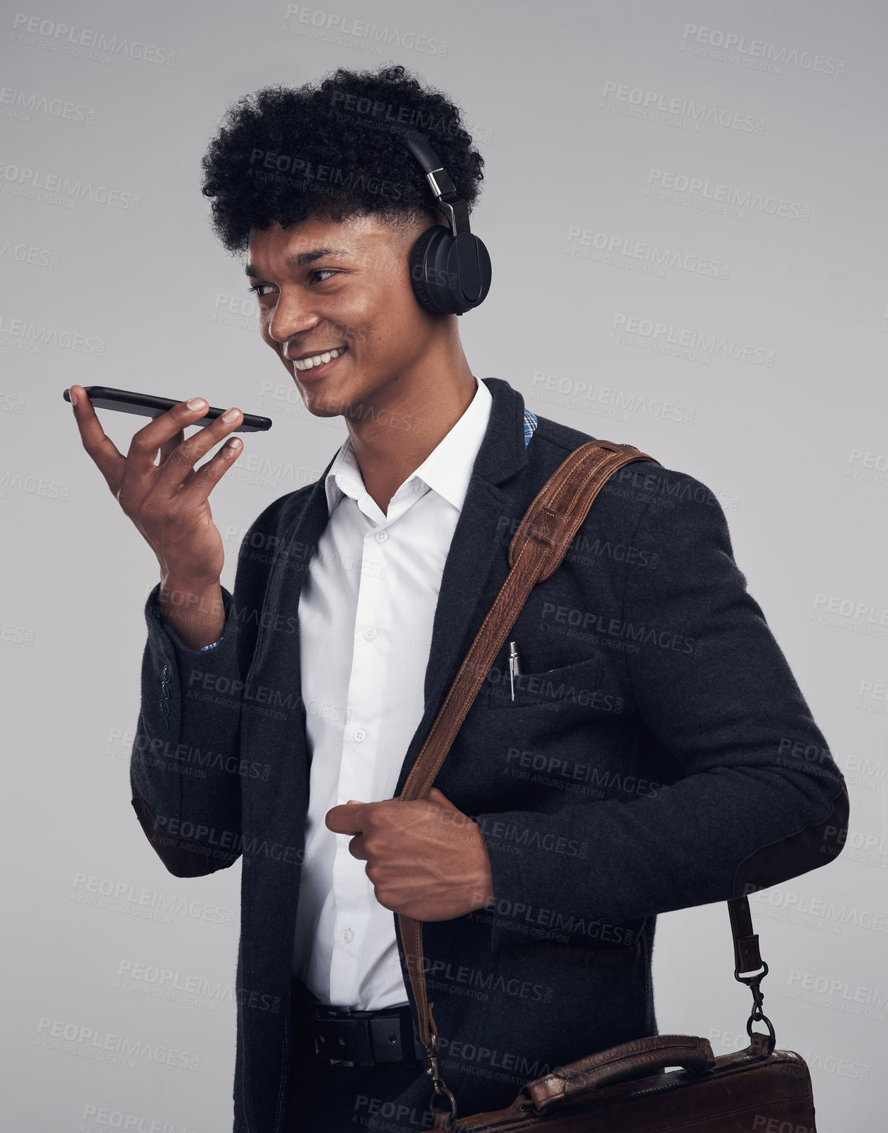 Buy stock photo Studio shot of a young businessman using a smartphone and headphones against a grey background