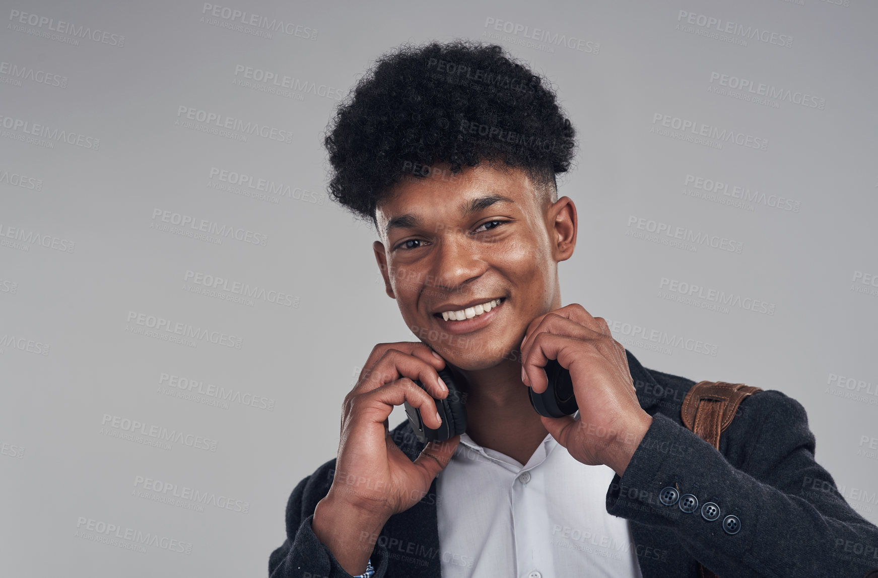 Buy stock photo Portrait of a young businessman using headphones against a grey background