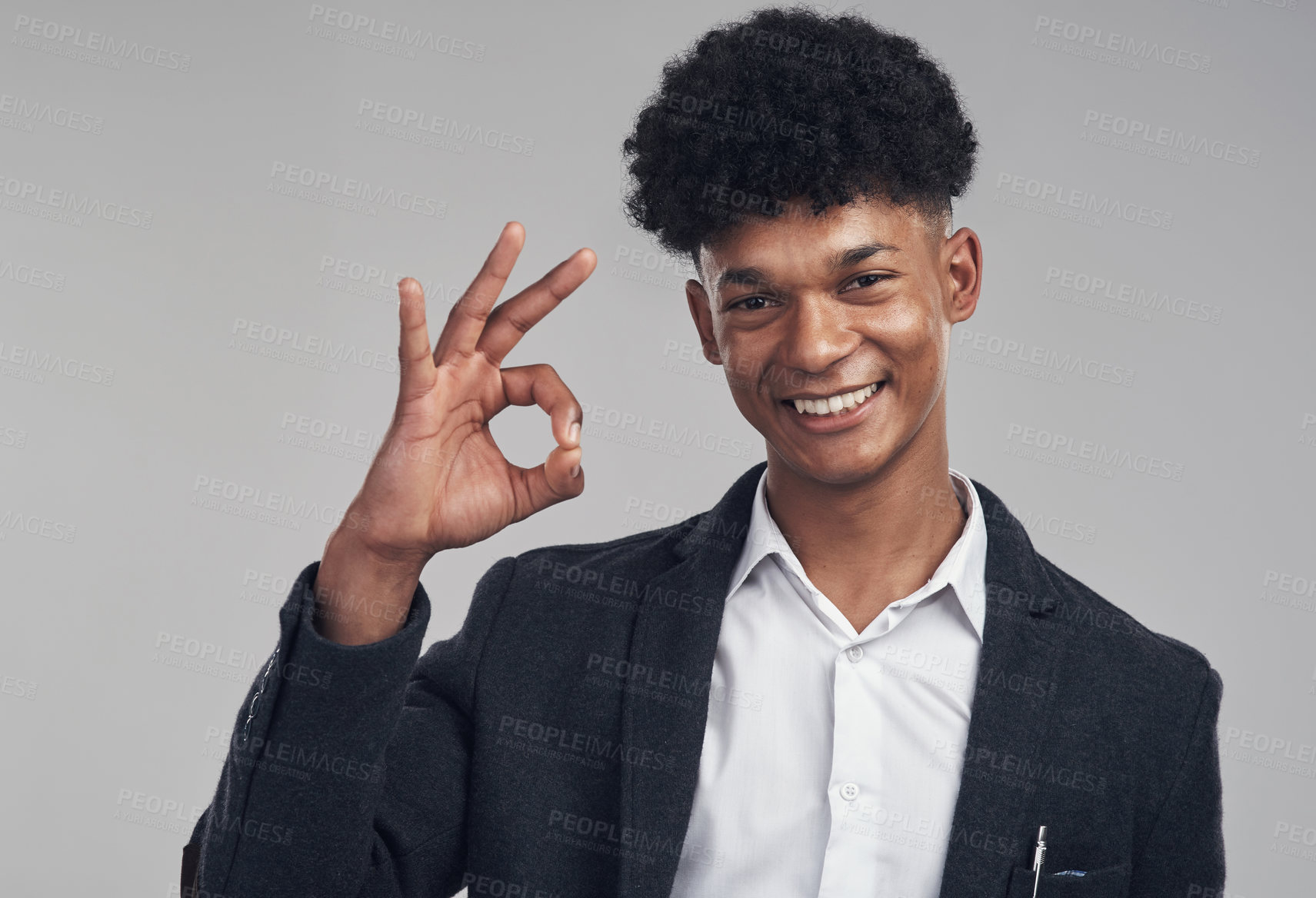 Buy stock photo Studio shot of a young businessman showing an okay hand gesture against a grey background