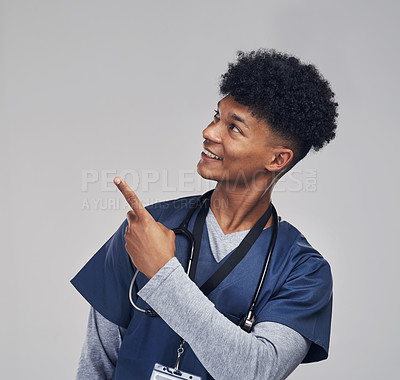 Buy stock photo Shot of a male nurse pointing at copy space while standing against a grey background