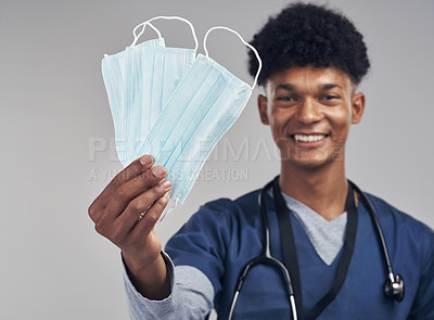 Buy stock photo Shot of a male nurse holding up a surgical masks while standing against a grey background