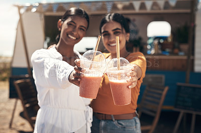 Buy stock photo Shot of two friends enjoying smoothies together