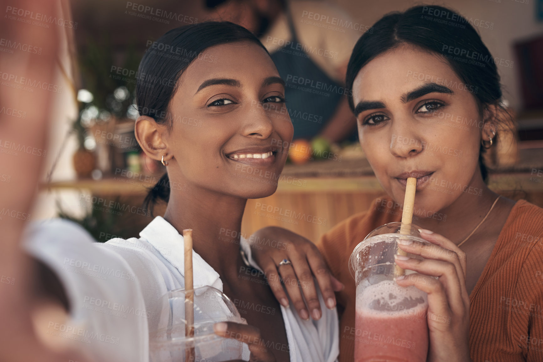 Buy stock photo Shot of two friends taking selfies while drinking smoothies