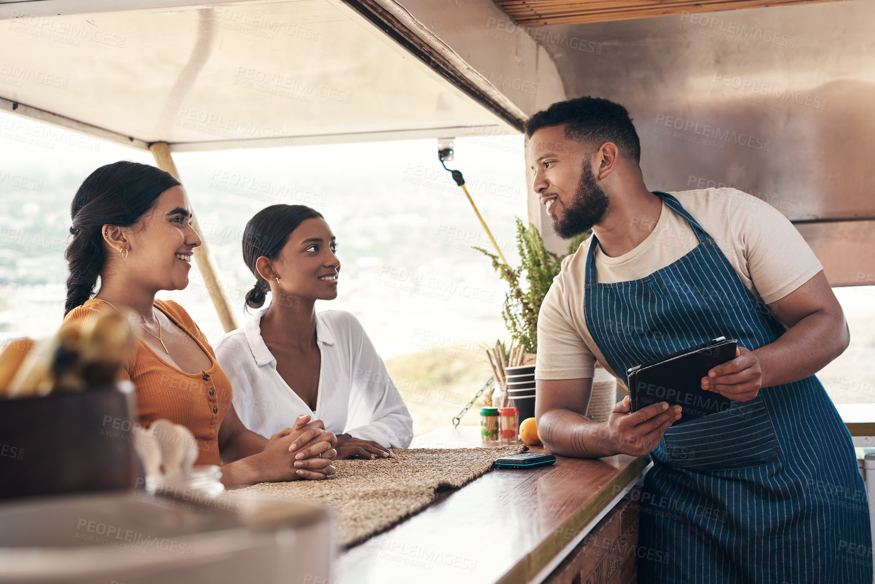 Buy stock photo Shot of two friends ordering food from a food truck