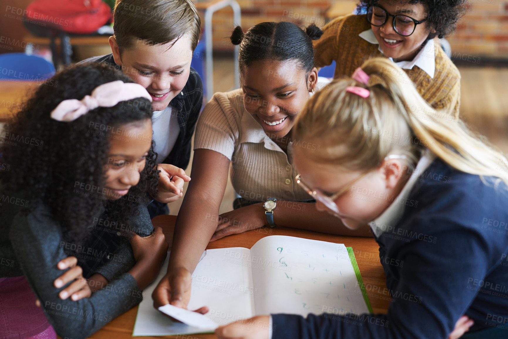 Buy stock photo Shot of a diverse group of children huddled together in their school classroom and reading a note