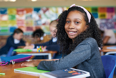 Buy stock photo Shot of a young girl sitting at her desk in her classroom at school during the day