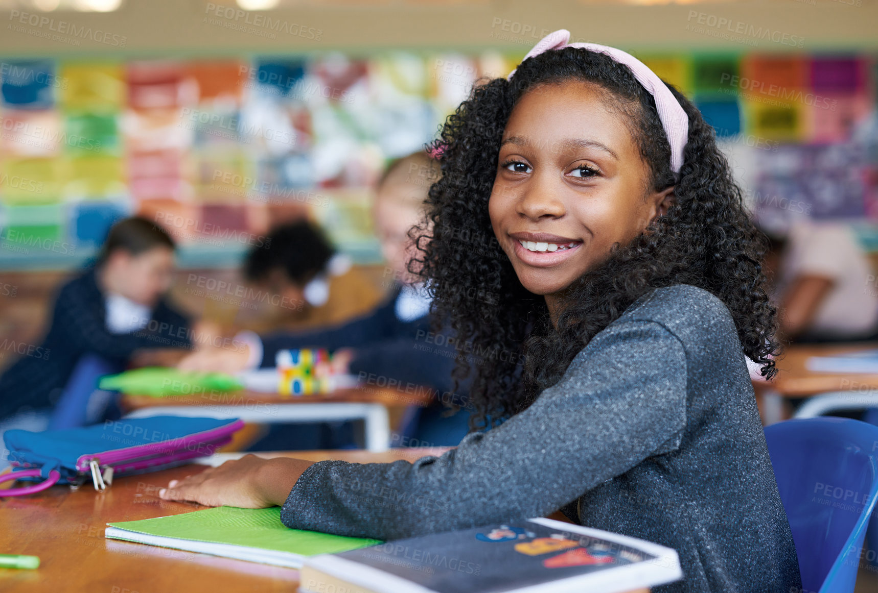 Buy stock photo Shot of a young girl sitting at her desk in her classroom at school during the day