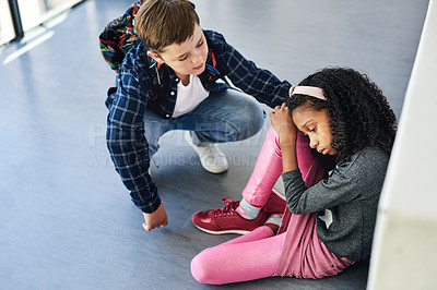 Buy stock photo Full length shot of a young girl sitting in the school hallway and feeling depressed while a classmate comforts her