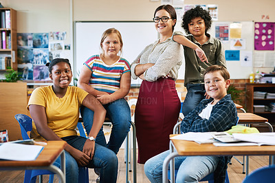 Buy stock photo Shot of an attractive young teacher posing with her students in her classroom at school