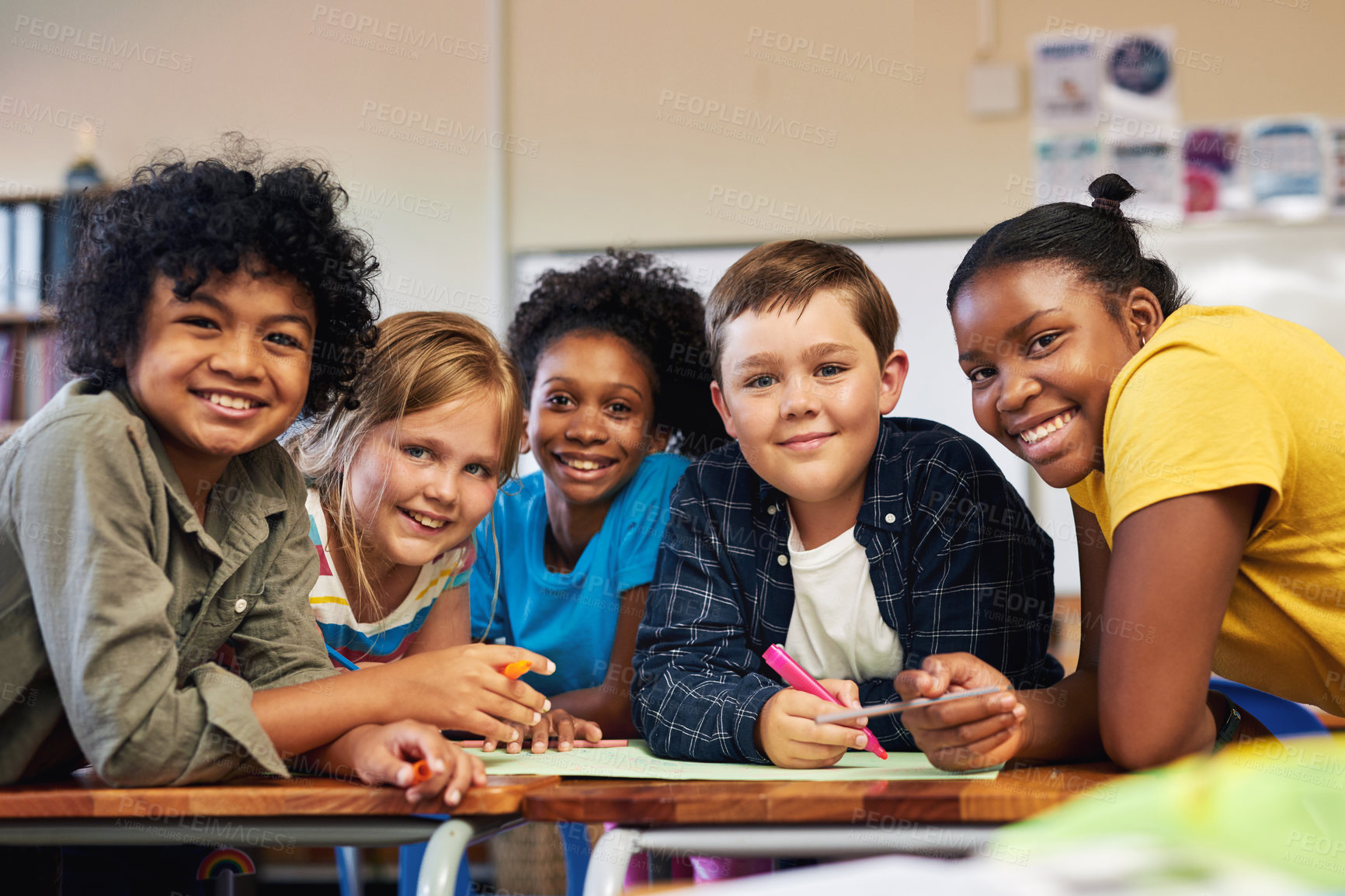 Buy stock photo Shot of a diverse group of children huddled together and colouring in their classroom at school