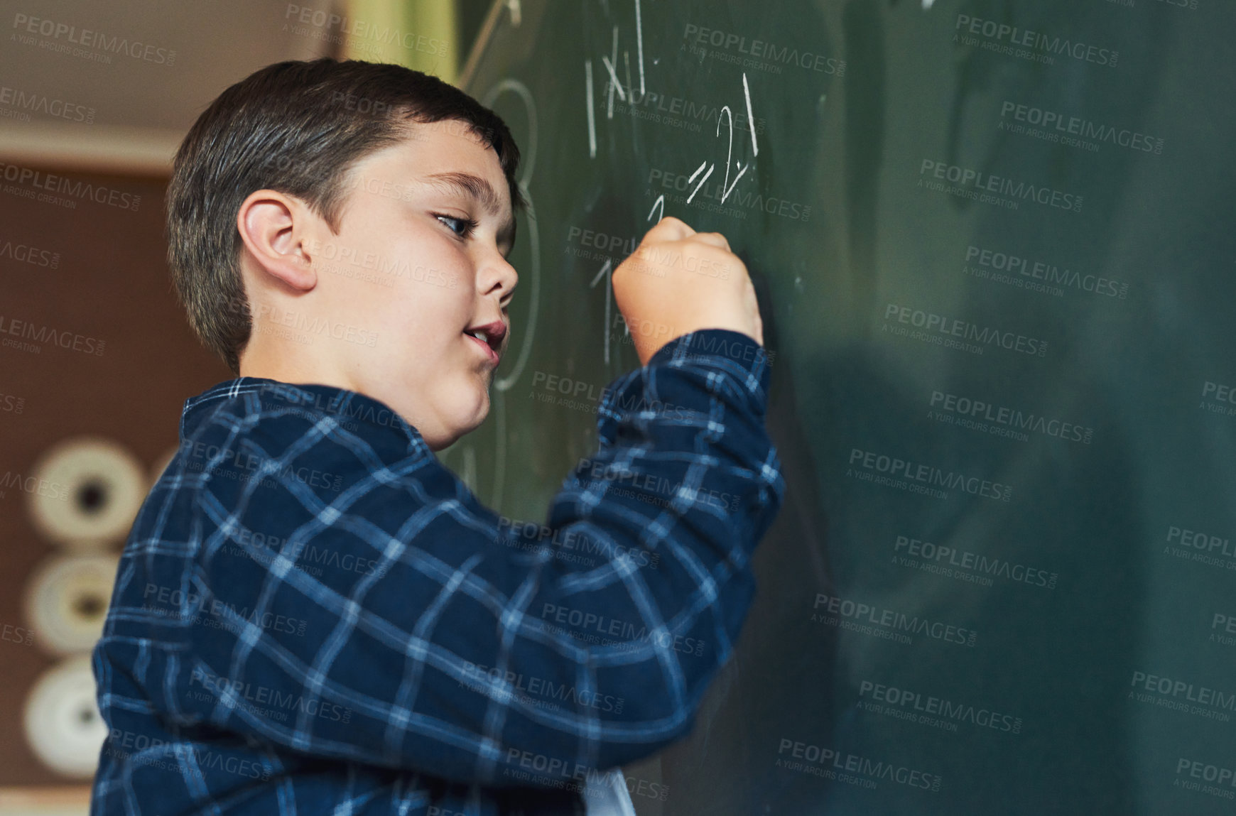 Buy stock photo Shot of a young boy standing alone and writing on the blackboard during a lesson in his classroom at school