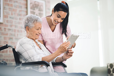 Buy stock photo Shot of a young nurse sharing information from her digital tablet with an older woman in a wheelchair