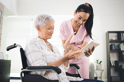 Buy stock photo Shot of a young nurse sharing information from her digital tablet with an older woman in a wheelchair