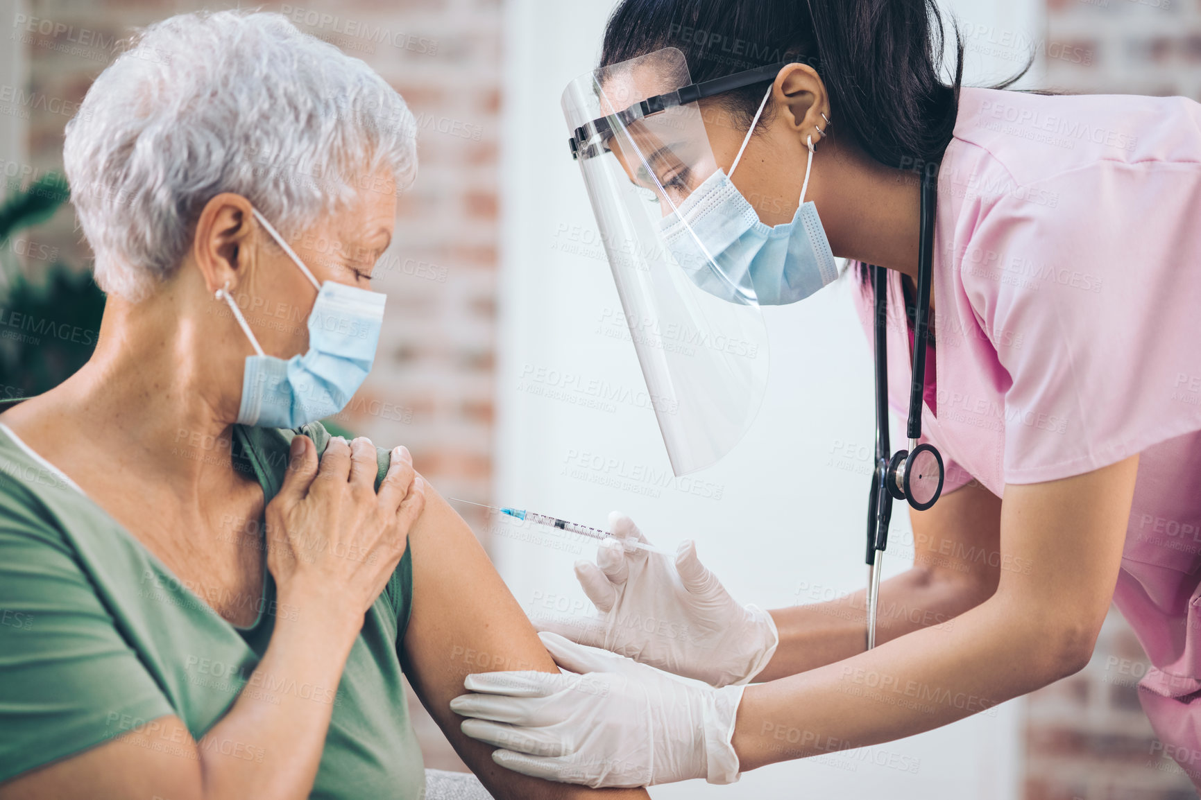 Buy stock photo Shot of a doctor giving a masked older woman an injection at home