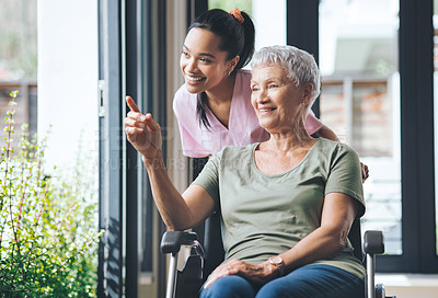Buy stock photo Shot of a young nurse standing beside an older woman in a wheelchair