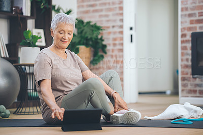 Buy stock photo Shot of an older woman using a digital tablet while sitting in the floor at home