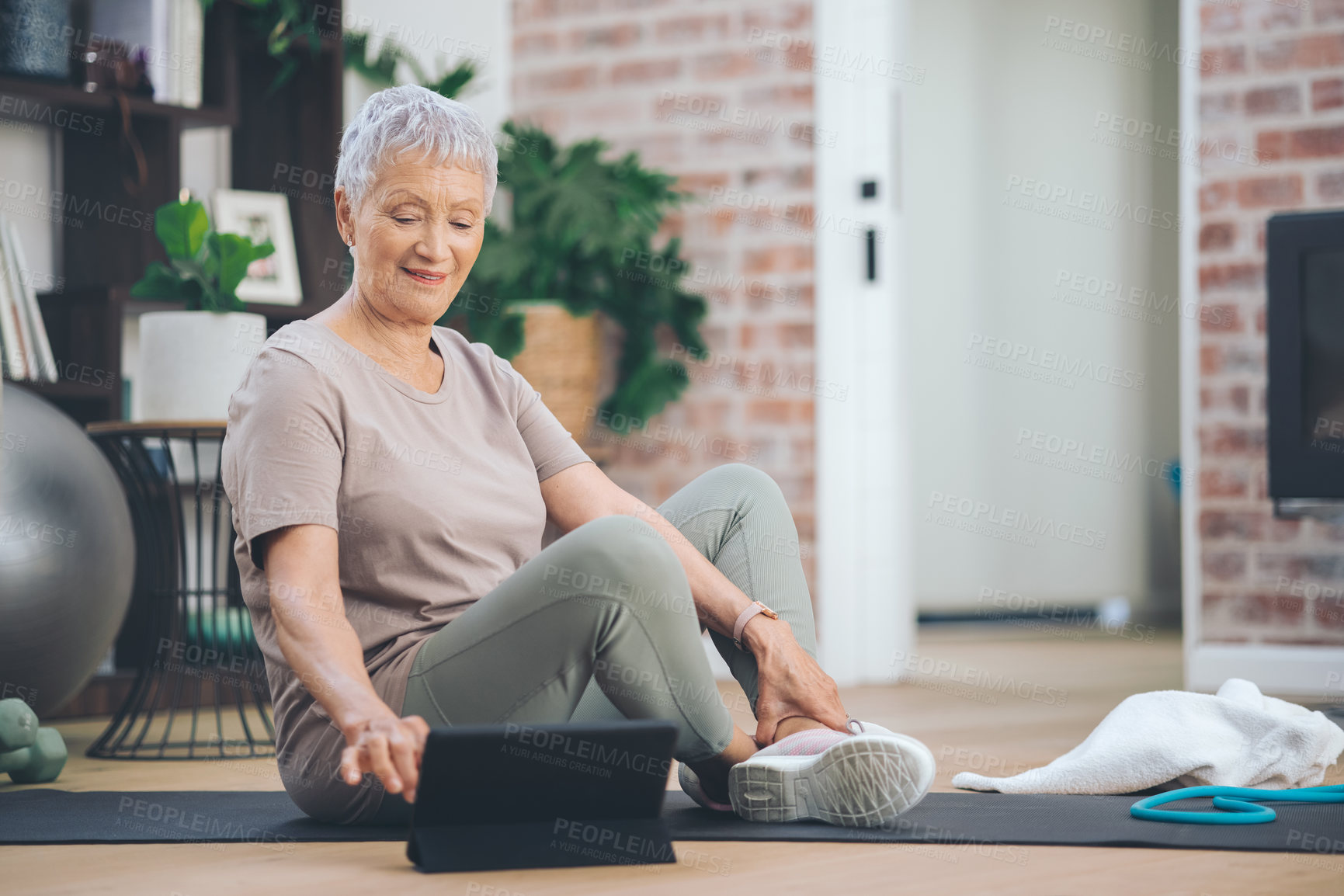 Buy stock photo Shot of an older woman using a digital tablet while sitting in the floor at home