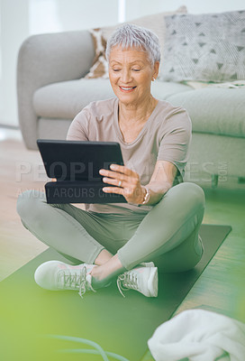 Buy stock photo Shot of an older woman using a digital tablet while sitting in the floor at home