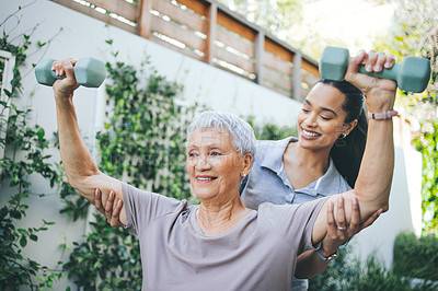Buy stock photo Shot of an older woman lifting dumbbells during a session with a physiotherapist