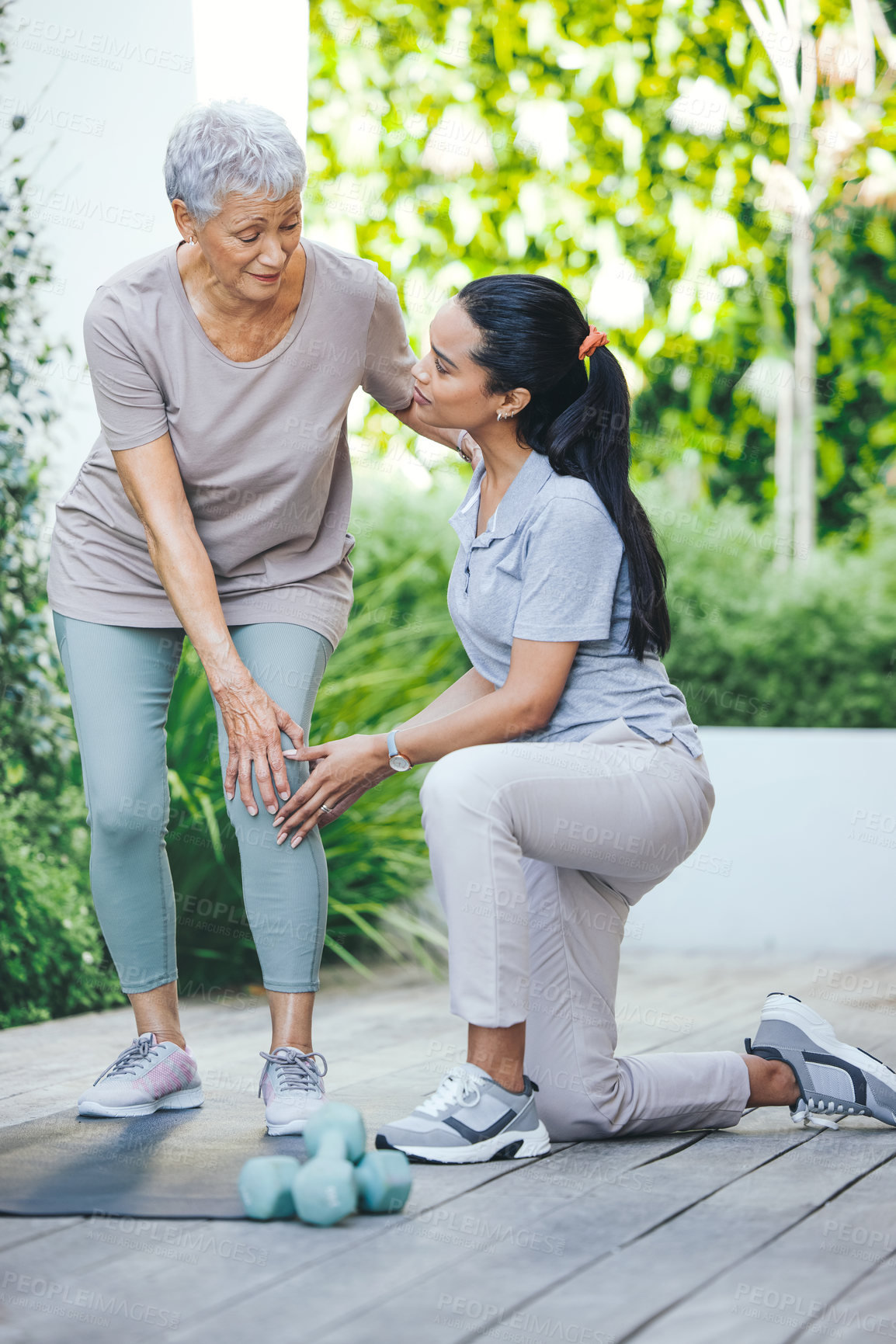 Buy stock photo Shot of an older woman holding an injured knee during a session with a physiotherapist