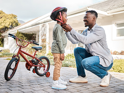 Buy stock photo Shot of a father adjusting a safety helmet on his son while riding a bicycle outdoors