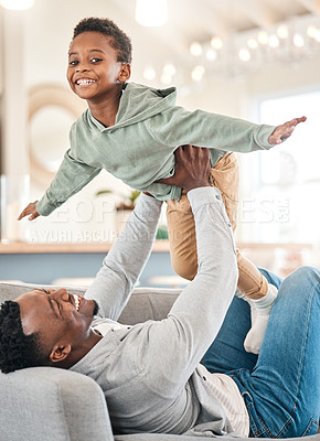 Buy stock photo Shot of an adorable little boy having fun with his father on the sofa at home