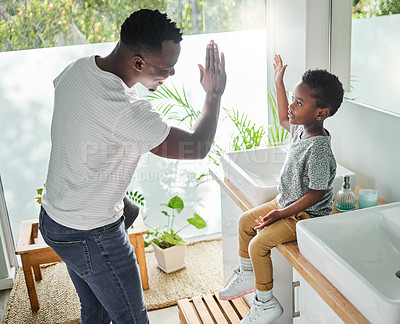 Buy stock photo High angle shot of a father giving his son a high five in a bathroom at home