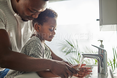 Buy stock photo Shot of a father helping his son wash his hands at a tap in a bathroom at home