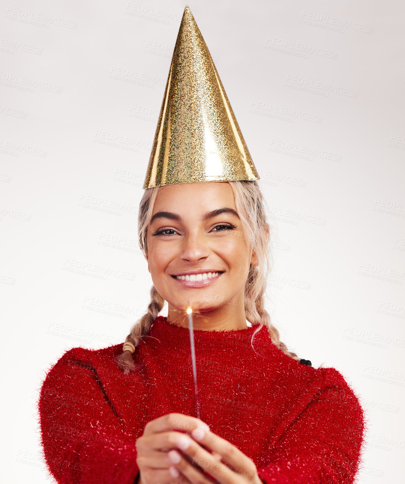 Buy stock photo Studio shot of a young woman wearing a party hat while holding a sparkler against a grey background