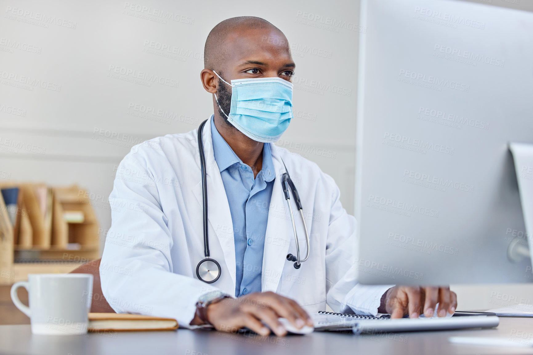 Buy stock photo Shot of a young doctor using a computer at work