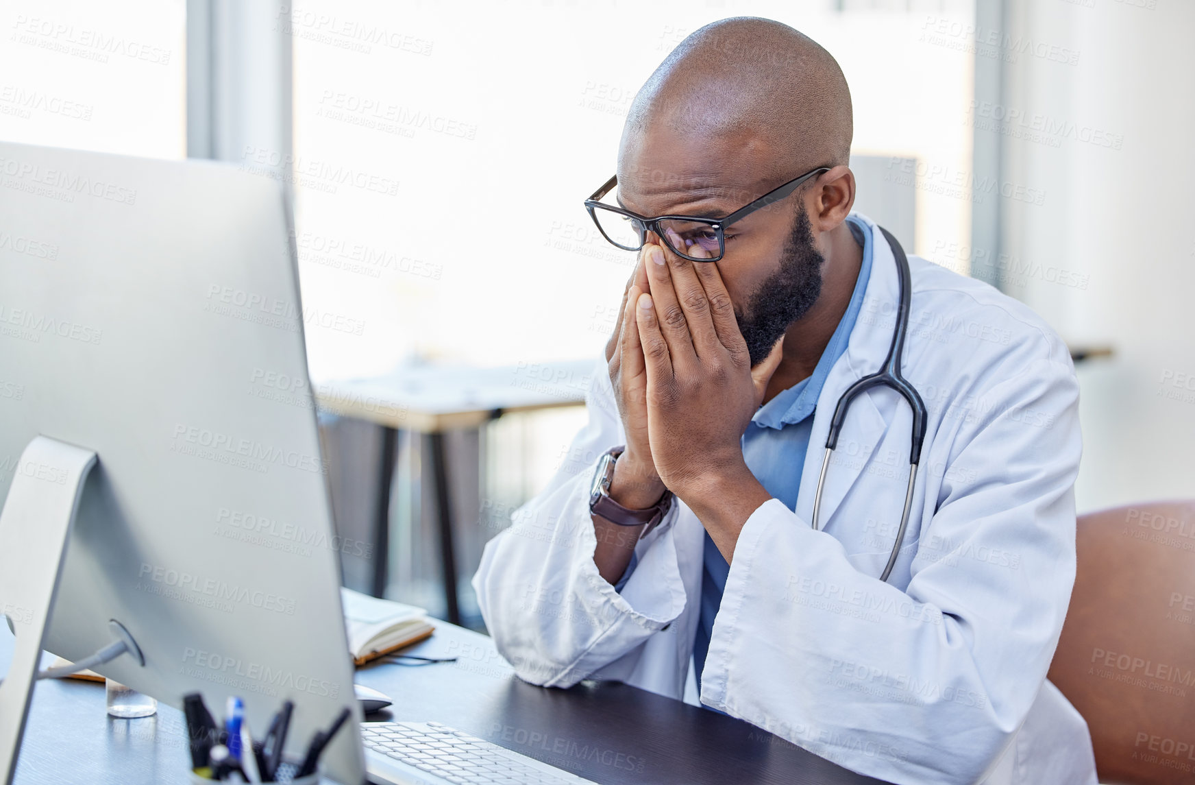 Buy stock photo Shot of a young doctor suffering from a headache at work