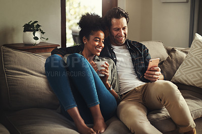 Buy stock photo Shot of a happy young couple using a digital tablet while relaxing on a couch in their living room at home