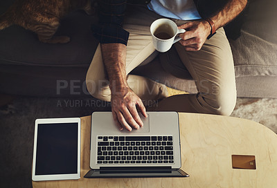Buy stock photo High angle shot of an unrecognizable man using his laptop while relaxing on a couch at home