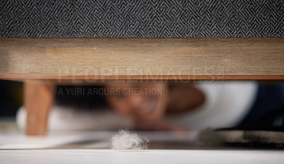 Buy stock photo Shot of an unrecognizable woman finding a ball of dust under the sofa in the living room at home