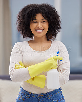 Buy stock photo Shot of an attractive young woman standing alone at home and holding a spray bottle while doing her chores