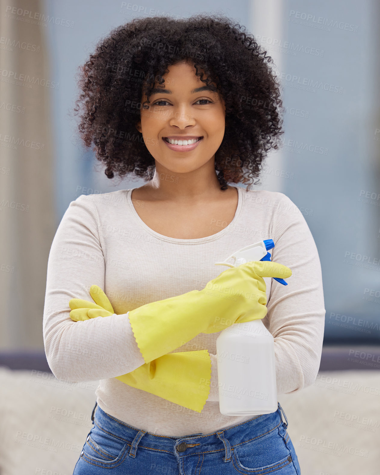 Buy stock photo Shot of an attractive young woman standing alone at home and holding a spray bottle while doing her chores