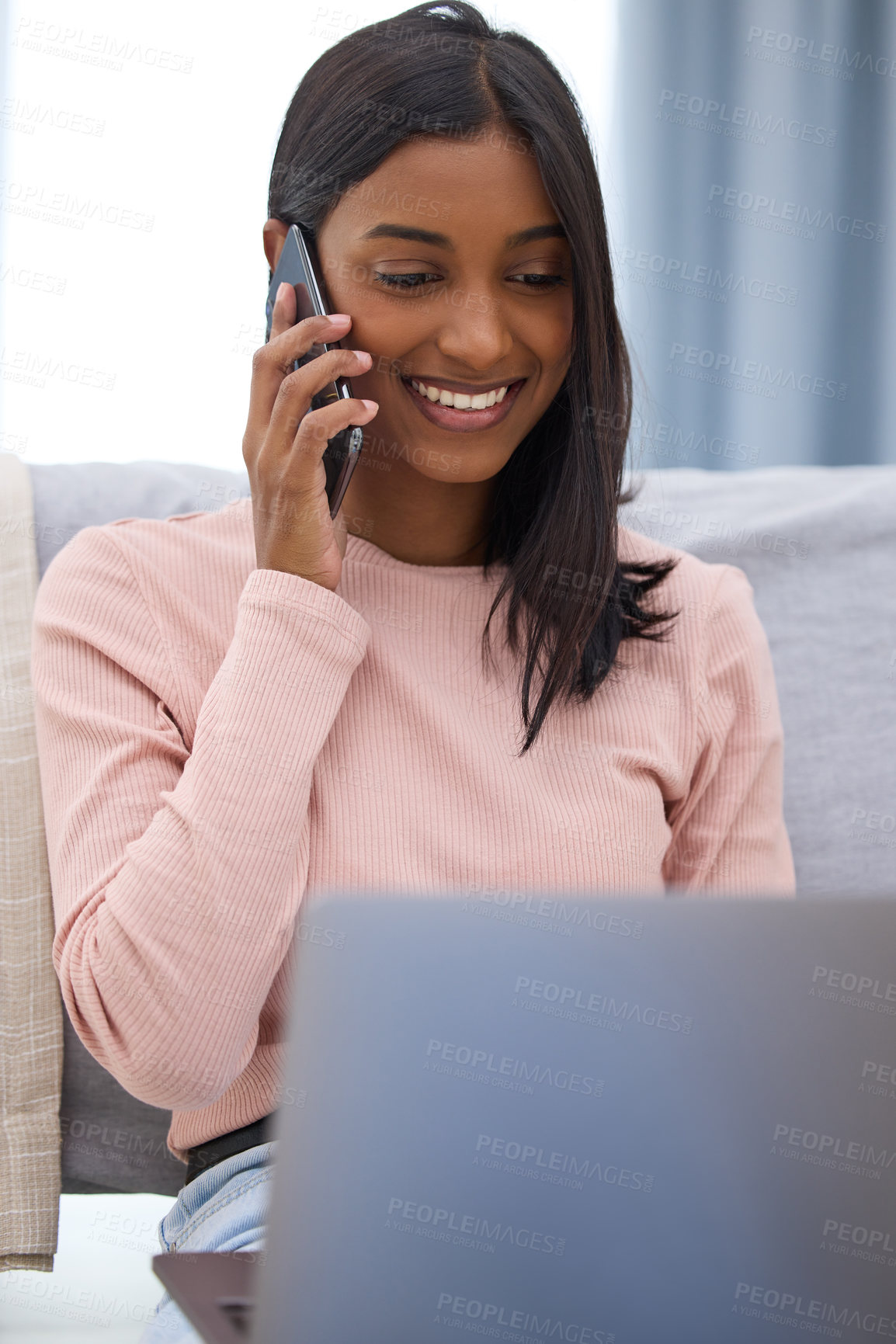 Buy stock photo Cropped shot of an attractive young woman making a phonecall while using her laptop in the bedroom at home