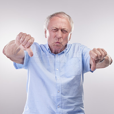 Buy stock photo Studio shot of a senior man showing thumbs down against a grey background