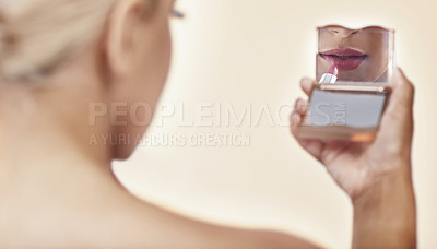 Buy stock photo Rearview shot of a woman applying lipstick while looking into a pocket mirror
