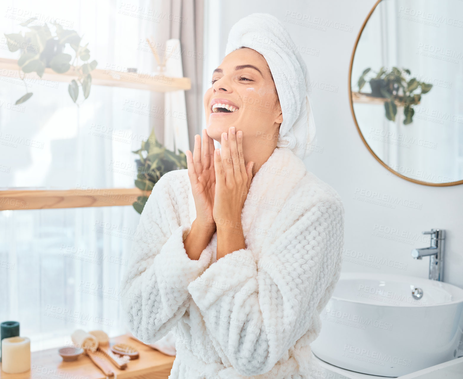 Buy stock photo Shot of a young woman applying moisturiser to her skin in her bathroom