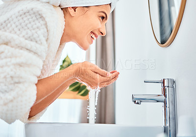 Buy stock photo Shot of a young woman washing her face in her bathroom