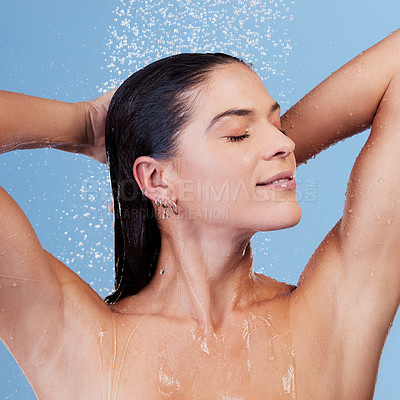 Buy stock photo Studio shot of a young woman taking a shower against a blue background