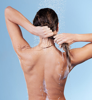 Buy stock photo Studio shot of a young woman rinsing her hair while taking a shower against a blue background