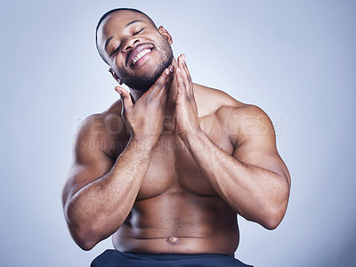 Buy stock photo Studio shot of a handsome young man feeling his skin against a blue background