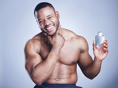 Buy stock photo Studio shot of a handsome young man applying cologne against a blue background