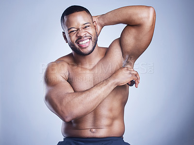 Buy stock photo Studio shot of a handsome young man applying deodorant against a blue background
