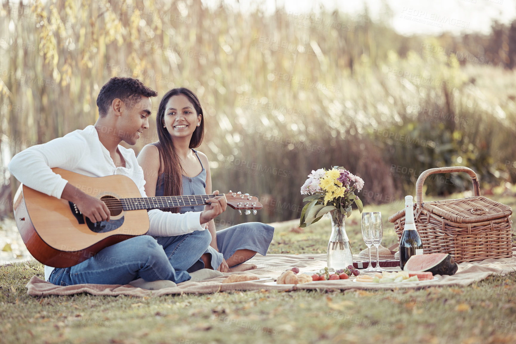 Buy stock photo Man, woman and date with picnic, guitar and romance for love or relationship anniversary. Couple, nature and lake with music, happiness and summer passion with bouquet for valentines celebration