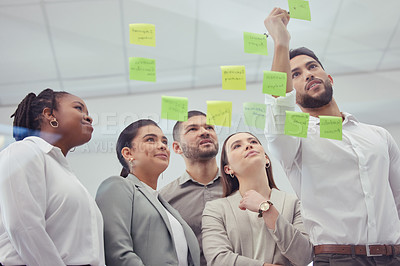Buy stock photo Business people, meeting and writing with team on glass board for brainstorming, ideas or tasks at office. Group of employees thinking with sticky note  or reminder for planning, process or schedule