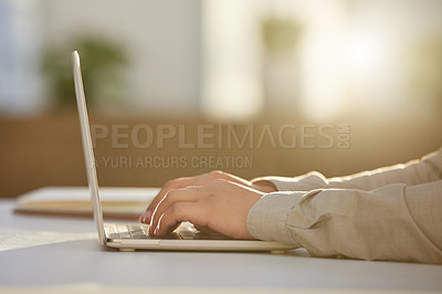 Buy stock photo Cropped shot of an unrecognizable businessman sitting alone in the office and using his laptop